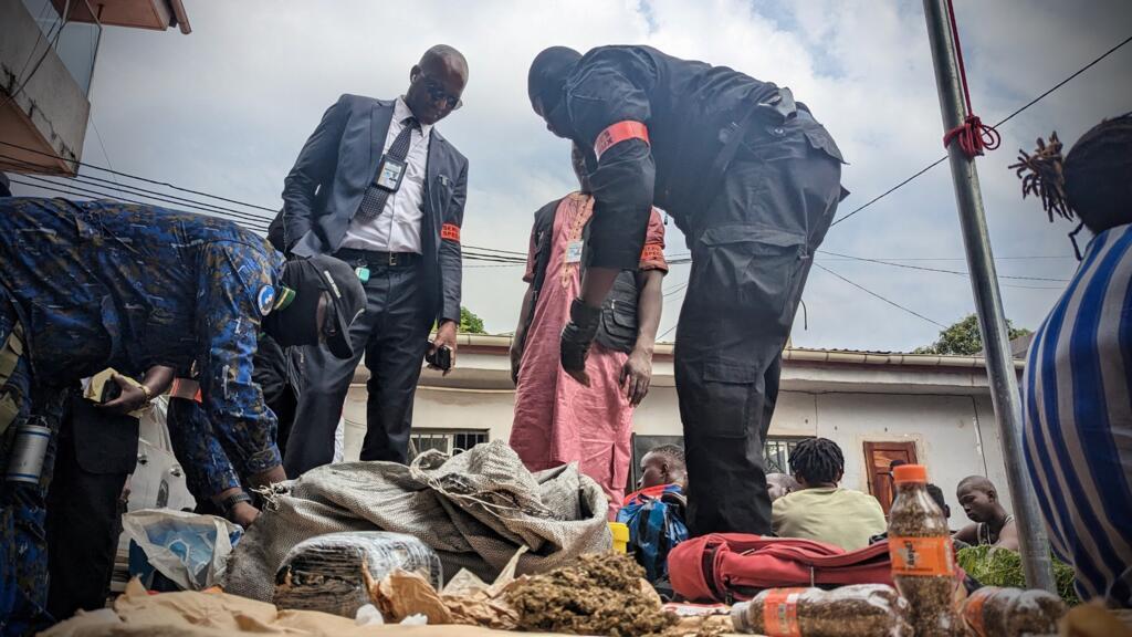 Le secrétaire général des services spéciaux, Abdoul Malick Koné, penché au-dessus d'une saisie de drogue, dont plusieurs doses de kush, à Conakry en Guinée, en 2022. 